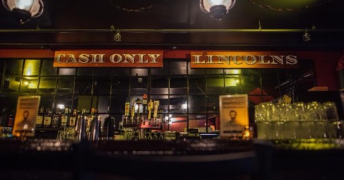 Dimly lit speakeasy in Burlington VT that says "cash only" over the bar