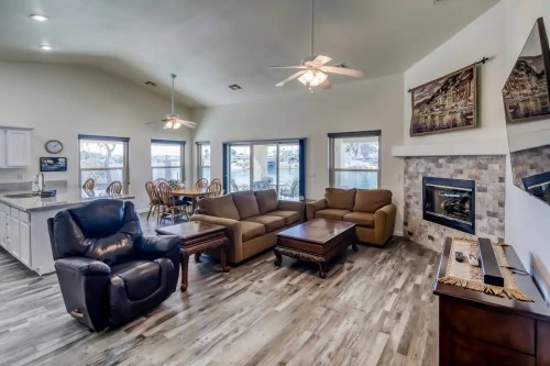 Cozy living room with a fireplace, comfortable seating, and dining area, featuring large windows and modern decor.