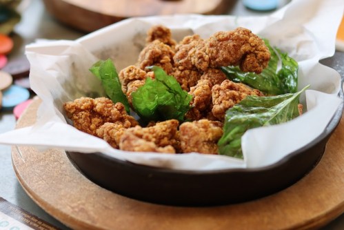 Crispy fried chicken pieces served in a bowl with fresh green leaves.