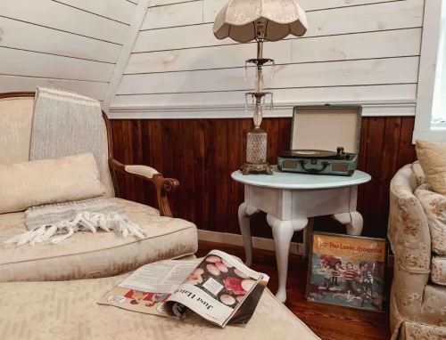 Cozy corner with a vintage lamp, a record player, a magazine, and a comfortable chair against a wooden wall.
