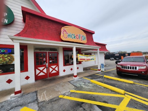 Exterior of Chick O Fish restaurant with a red roof, drive-thru open sign, and a parked car in the lot.