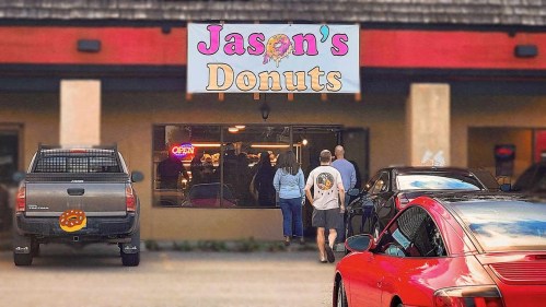 A colorful sign for "Jason's Donuts" with people entering the shop and cars parked outside.