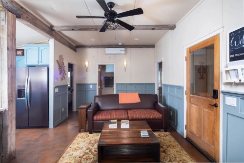 Cozy living room with a brown sofa, wooden coffee table, and a ceiling fan, featuring blue and white walls.