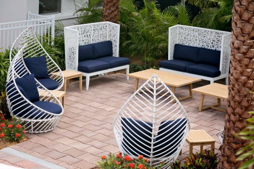 A stylish outdoor seating area with white furniture, navy cushions, and tropical plants.