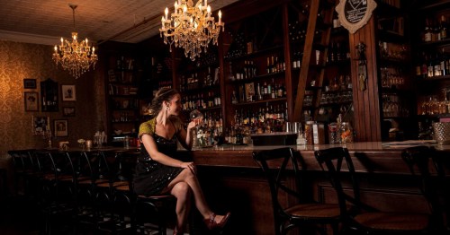 A woman sits at a bar in a speakeasy-inspired space