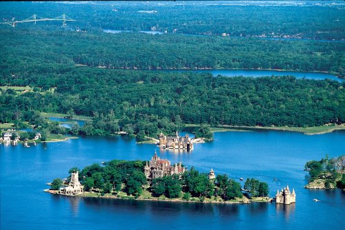 Aerial view of a lush green landscape with islands and a lake, featuring historic buildings and bridges in the distance.