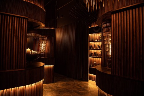 A dimly lit interior featuring wooden walls, warm lighting, and decorative shelves, creating a cozy atmosphere.