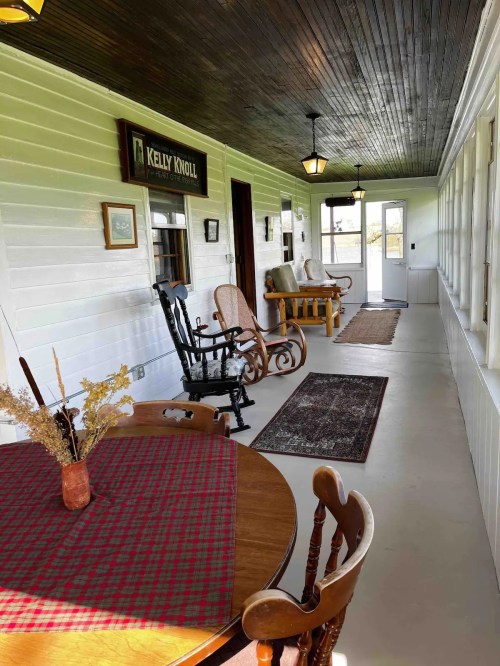 A cozy porch with wooden furniture, a table with a checkered cloth, and decorative lighting.