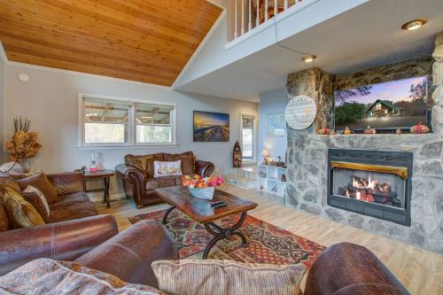Cozy living room with a stone fireplace, leather sofas, and wooden ceiling, featuring a warm, inviting atmosphere.