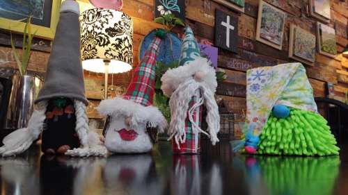 Four whimsical gnome decorations with various hats and beards, displayed on a wooden table in a cozy setting.