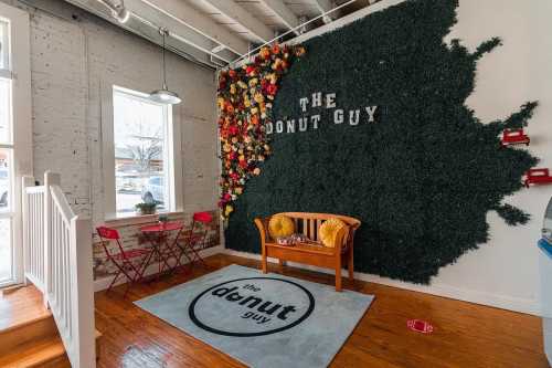 Cozy interior of a donut shop featuring a floral wall, seating area, and branded rug.