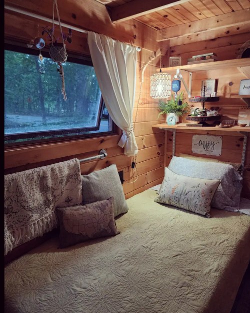 Cozy wooden interior with a bed, decorative pillows, and a window, creating a warm, inviting atmosphere.