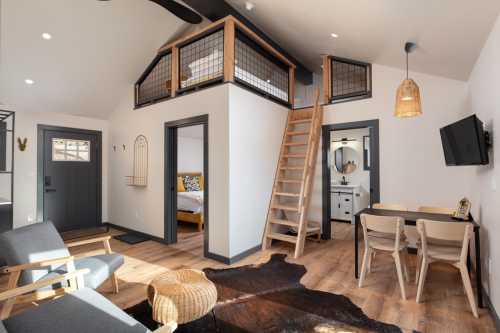 Cozy interior of a modern cabin featuring a loft, dining area, and stylish decor with wooden accents.