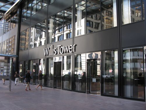Exterior view of Willis Tower with large glass windows and people walking by.