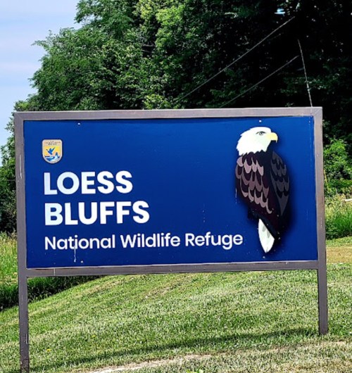 Sign for Loess Bluffs National Wildlife Refuge featuring an eagle graphic against a blue background.