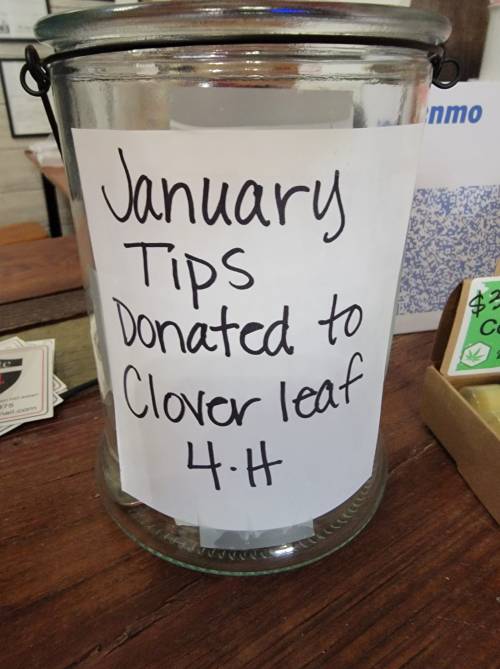 A glass jar with a sign that reads "January Tips Donated to Clover Leaf 4-H."