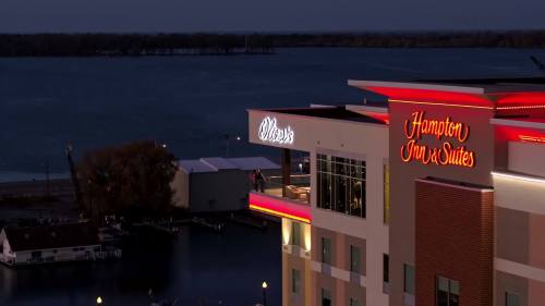 View of Hampton Inn & Suites at dusk, with a lake in the background and illuminated signage.