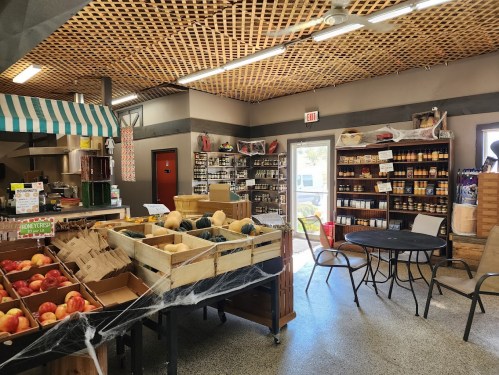 A cozy market interior with wooden shelves, fresh produce, and jars of goods, featuring a welcoming atmosphere.