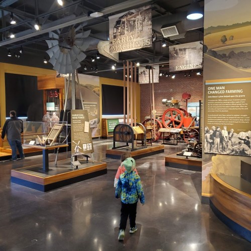 A child walks through a museum exhibit featuring early farming machines and historical displays.