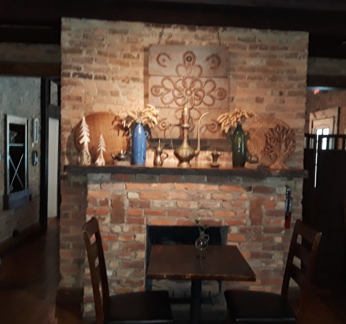 Cozy restaurant interior featuring a brick wall, decorative vases, and a small table with chairs.