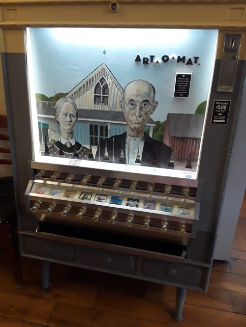 A vintage vending machine with art pieces, featuring a mural of a couple in front of a barn.