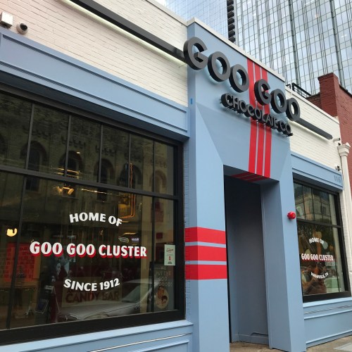 Exterior of Goo Goo Chocolate Co. with a sign reading "Home of Goo Goo Cluster Since 1912" and a modern design.