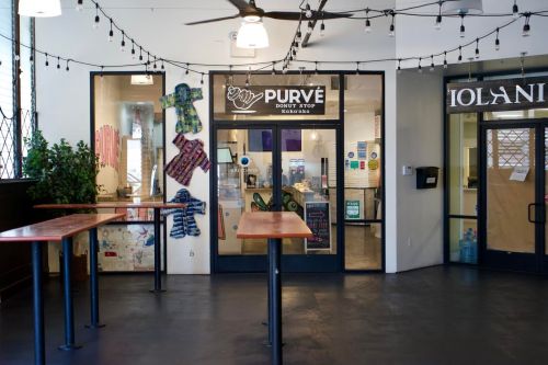 A cozy café entrance with wooden tables, string lights, and colorful decorations on the walls.