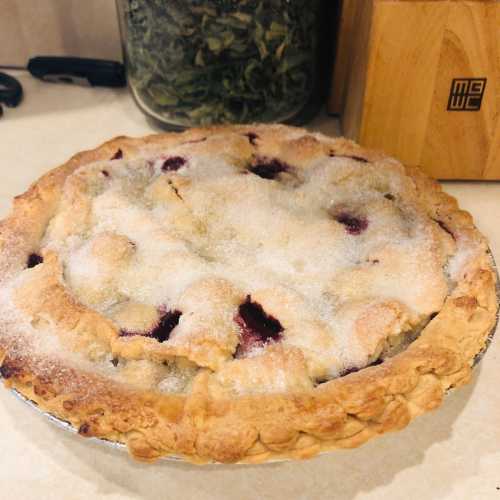 A freshly baked pie with a golden crust and a sugary topping, sitting on a countertop.