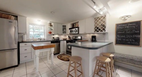 Cozy kitchen with stainless steel appliances, a small island, and a chalkboard with welcome information.