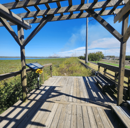 A wooden observation deck with benches, overlooking a scenic landscape under a clear blue sky.