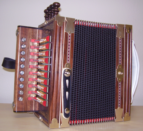 A wooden accordion with red and silver buttons, featuring a black bellows and decorative details.