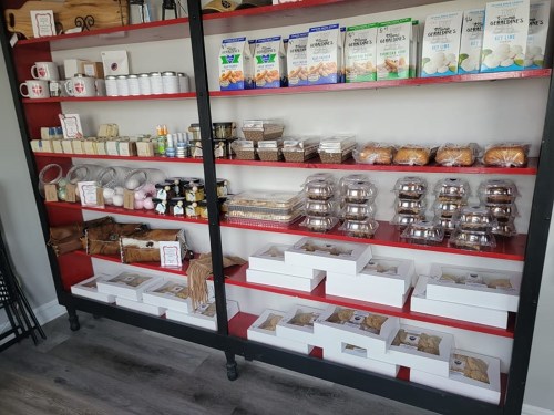 A display shelf filled with various baked goods, jars, and packaged treats in a cozy shop setting.
