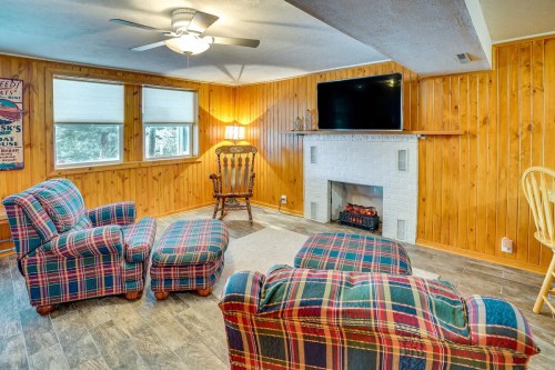 Cozy living room with plaid chairs, a fireplace, and a wall-mounted TV, featuring wooden paneling and natural light.