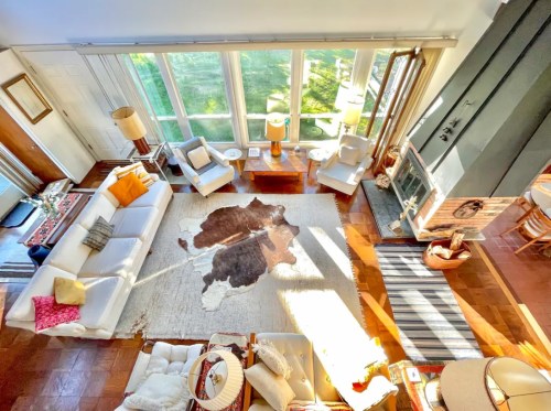 Bright living room with large windows, cozy seating, a cowhide rug, and warm lighting.