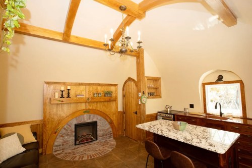 Cozy interior featuring a wooden beam ceiling, fireplace, and a kitchen with a marble countertop and rustic decor.