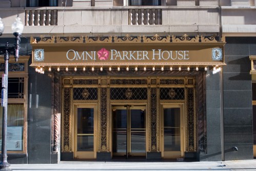 Entrance of the Omni Parker House hotel, featuring ornate gold detailing and large glass doors.