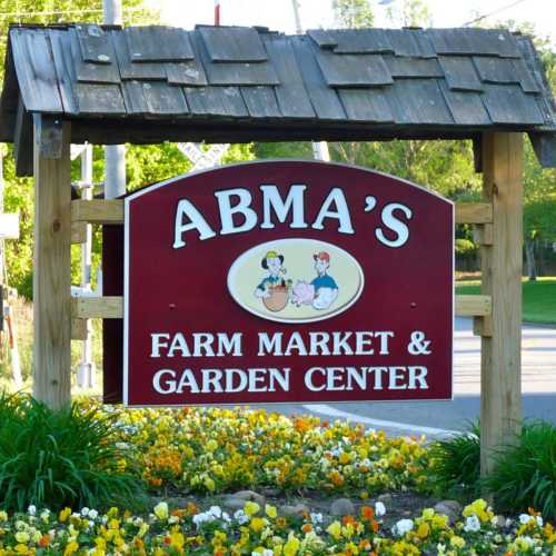 Sign for Abma's Farm Market & Garden Center, featuring a wooden structure and colorful flowers in the foreground.