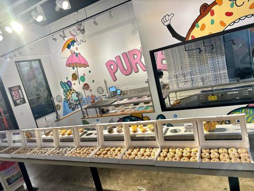 A colorful donut shop interior with a display case filled with various donuts and playful wall art.