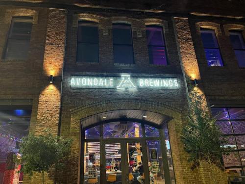 Exterior of Avondale Brewing Co. at night, featuring a lit sign and colorful lights on a brick building.