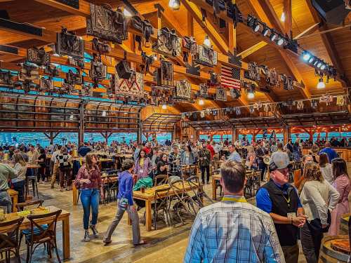 A bustling indoor venue with wooden decor, people socializing, and various items hanging from the ceiling.