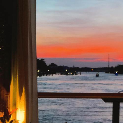 A serene sunset over a river, with vibrant orange and pink hues reflecting on the water.