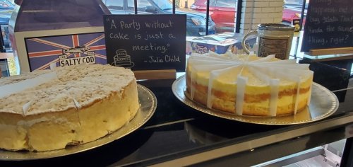 Two cakes displayed on a table, with a quote by Julia Child about cake and parties on a sign nearby.