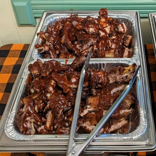 A close-up of trays filled with tender, sauced ribs, ready to be served.