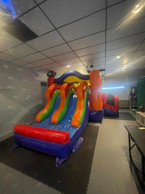 A colorful inflatable slide with multiple lanes, set up indoors in a spacious area.