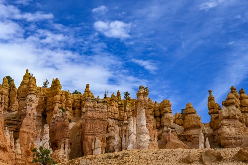 A landscape of unique rock formations under a blue sky with scattered clouds.