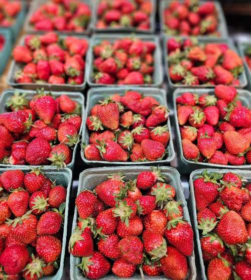 Baskets of fresh, ripe strawberries arranged neatly in a market display.