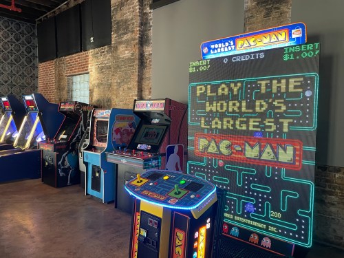 A retro arcade featuring various classic games, including a large Pac-Man machine with a colorful display.
