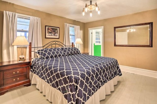 Cozy bedroom featuring a patterned bedspread, wooden nightstands, lamps, and a large mirror on the wall.