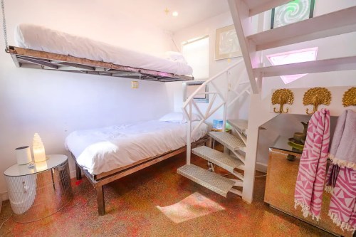 Cozy bedroom with a lofted bed, a lower bed, and colorful flooring, featuring a staircase and decorative accents.
