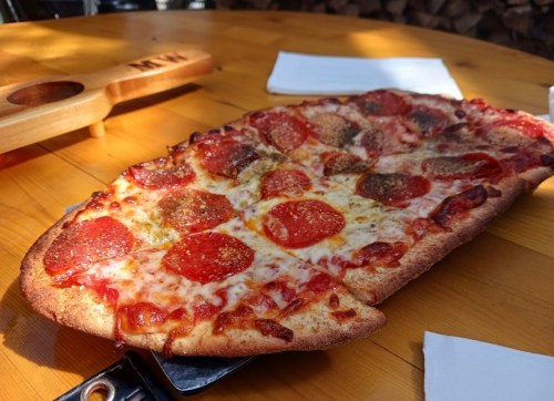 A freshly baked pepperoni pizza on a wooden table, with melted cheese and a crispy crust.